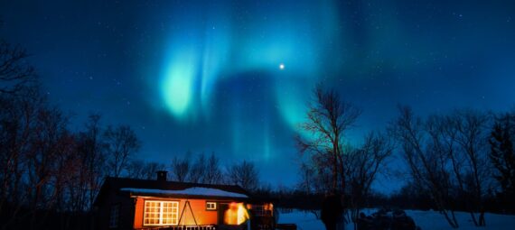 brown cottage under aurora borealis