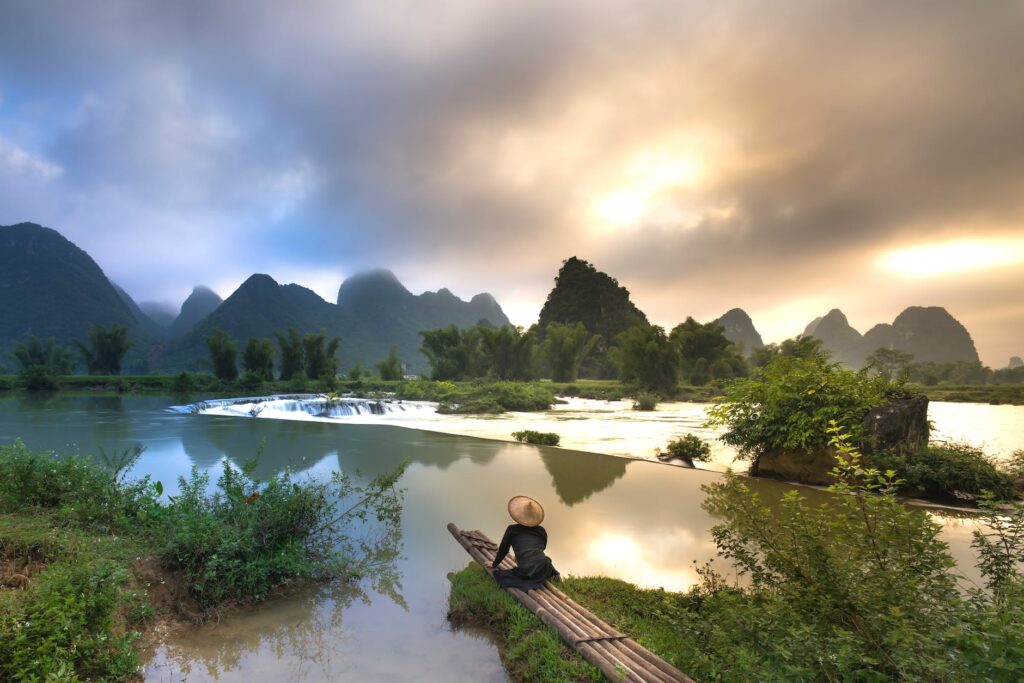 person sitting on bamboo near body of water