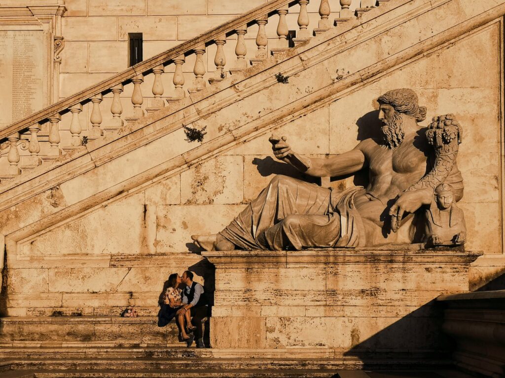 photo of couple kissing beside statue