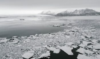 antarctic landscape with broken ice on water and frozen mounts